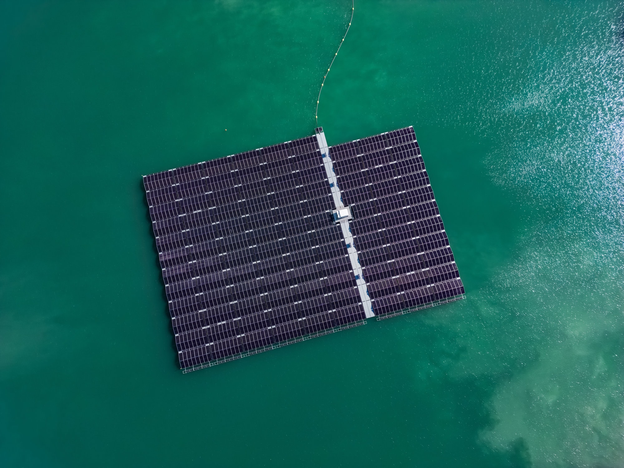 Vogelperspektive auf eine schwimmende Photovoltaik-Anlage in einem türkisfarbenen See